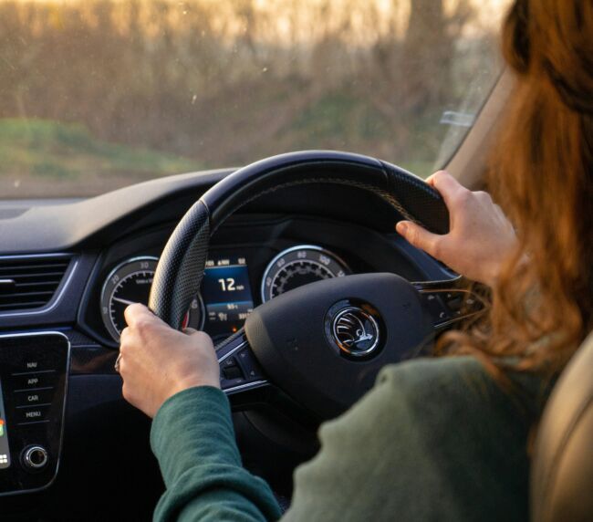 Close-up of a driver’s hands on a steering wheel, navigating the road