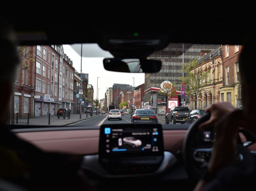 View from inside a taxi showing a busy street in Belfast, seen from the driver's perspective.