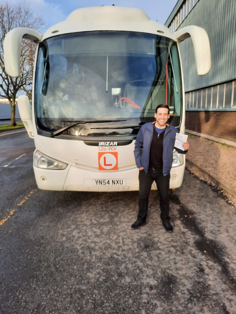 Marty smiling in front of a coach after passing his PCV test.