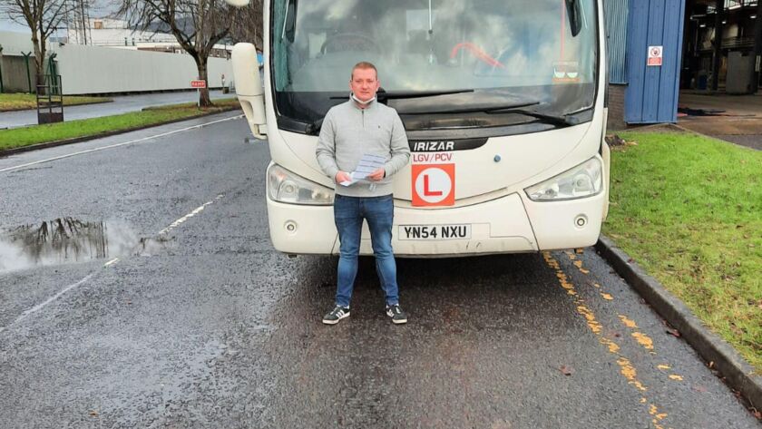 Jamie proudly holding his PCV test certificate in front of a new coach.