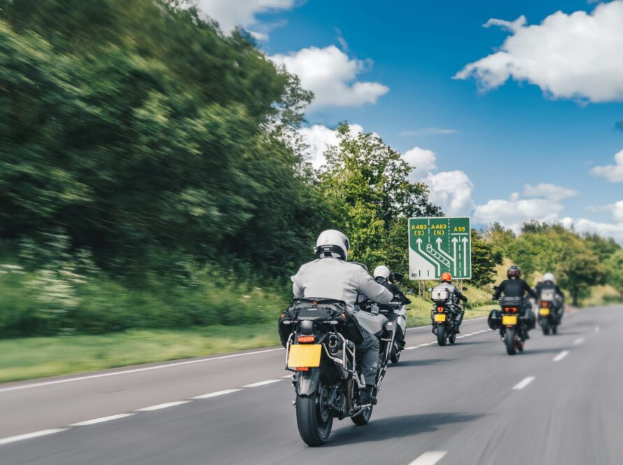 Group of motorcyclists with full gear riding together on a highway, showcasing advanced riding techniques in a real-world setting