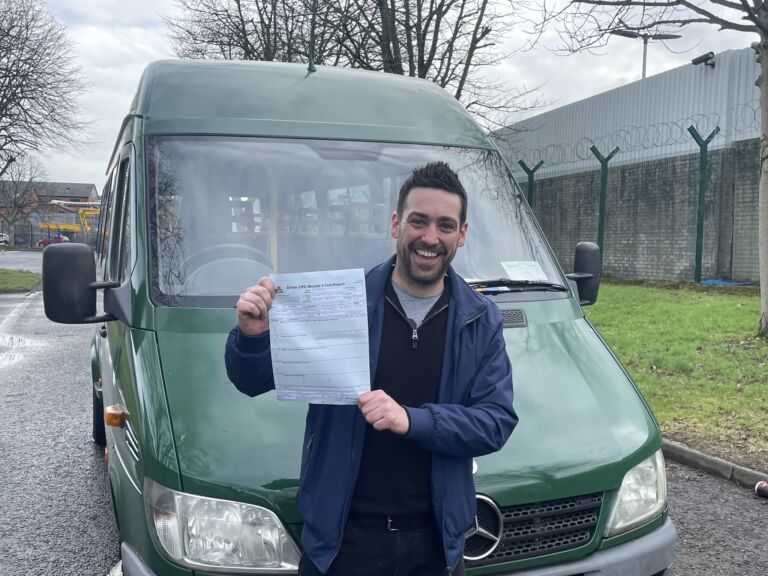 Man holding a driving certification in front of a green van